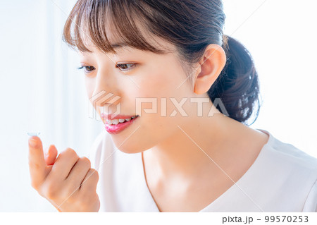 コンタクトレンズをつけようとする女性 99570253