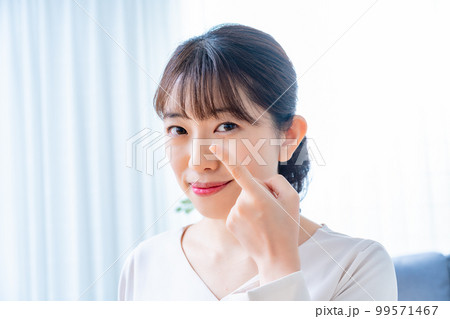 コンタクトレンズをつけようとする女性 99571467