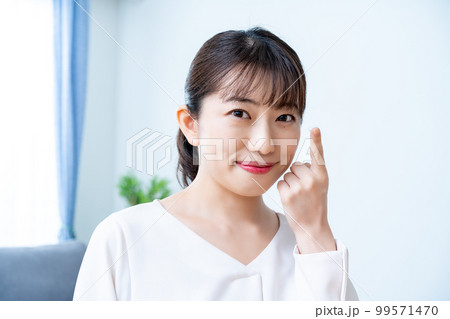 コンタクトレンズをつけようとする女性 99571470