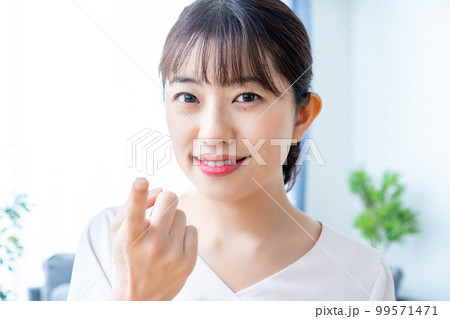 コンタクトレンズをつけようとする女性 99571471