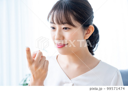 コンタクトレンズをつけようとする女性 99571474