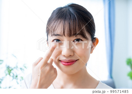 コンタクトレンズをつけようとする女性 99571485