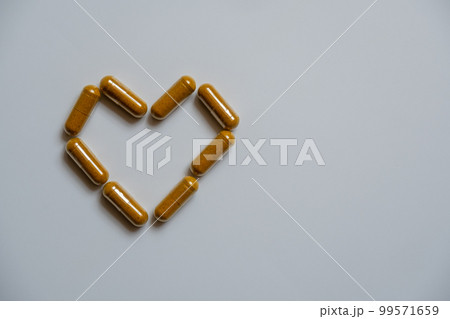 Several brown capsules, arranged in a heart shape 99571659