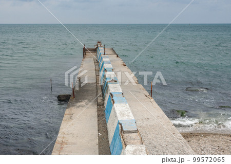 Stone pier on the emnankment of Feodosiain cloudy weather. Crimea 99572065