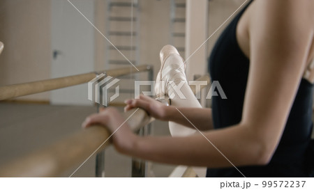 Female ballet dancer stands near ballet barre Female ballet dancer stands near ballet barre 99572237