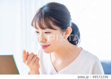 コンタクトレンズをつけようとする女性 99572296