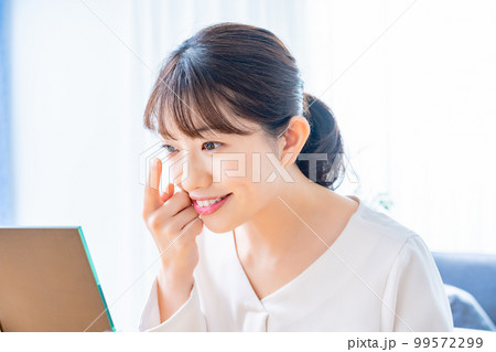 コンタクトレンズをつけようとする女性 99572299