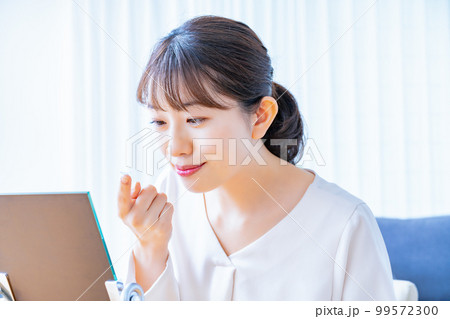 コンタクトレンズをつけようとする女性 99572300