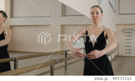 Adult ballerina rehearses near ballet barre Adult ballerina rehearses near ballet barre 99572312