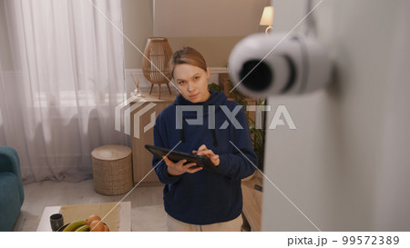 Woman installs CCTV camera using tablet Woman installs CCTV camera using tablet 99572389