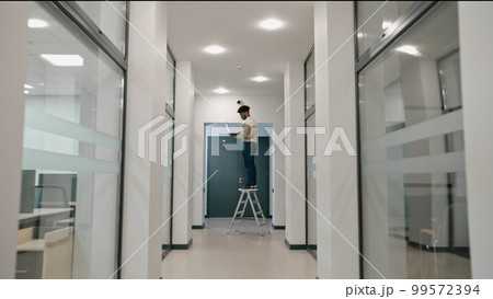 Man stays on ladder and checks CCTV cameras in computer program Man stays on ladder and checks CCTV cameras in computer program 99572394