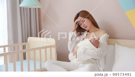 tired mother breastfeeding baby 99573491