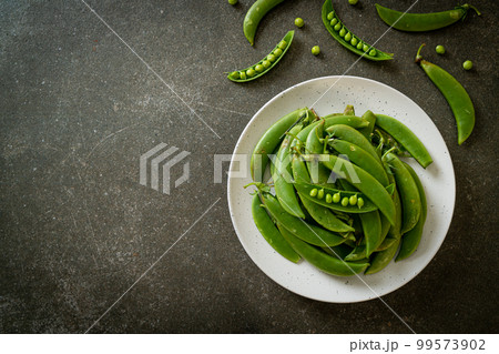fresh sweet green peas on plate 99573902