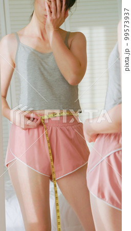unhappy woman measure her waist unhappy woman measure her waist 99573937