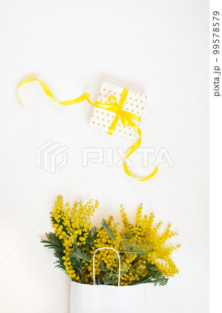 Yellow mimosa flowers frame with gift box. Womans day, easter , spring composition. Top view with copy space Yellow mimosa flowers frame with gift box. Womans day, easter , spring composition. Top view with copy space 99578579