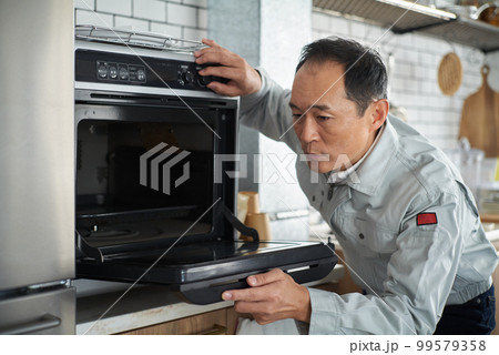 オーブンを点検する修理業者の男性 99579358