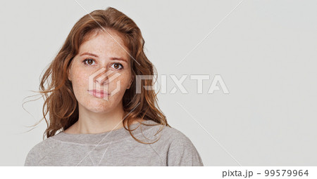 Portrait of a pretty young serious redhead woman posing isolated over white wall background Portrait of a pretty young serious redhead woman posing isolated over white wall background 99579964