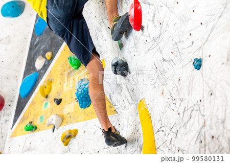 Close up view of young man or climber feet in climbing shoes on artificial indoor wall at climbing center, sport activity concept 99580131