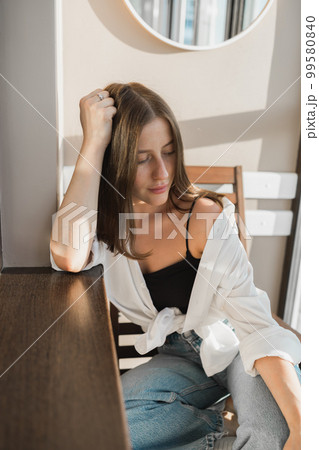 Happy young woman sit relaxing in comfortable chair feel peaceful enjoy sun near big windows, smiling girl lying with eyes closed rest calm sunny morning at home Happy young woman sit relaxing in comfortable chair feel peaceful enjoy sun near big windows, smiling girl lying with eyes closed rest calm sunny morning at home 99580840