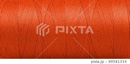 Texture of threads in a spool of Orange color on a white background Texture of threads in a spool of Orange color on a white background 99581334