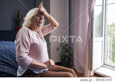 Senior woman suffering from a headache resting at home on sofa 99581597