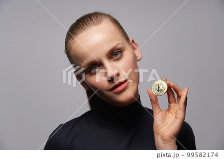 Closeup of young female holding Crypto coin symbol in hand. 99582174