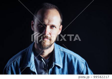 Concentraited middle age man in denim shirt looking squinting at camera Concentraited middle age man in denim shirt looking squinting at camera 99582217
