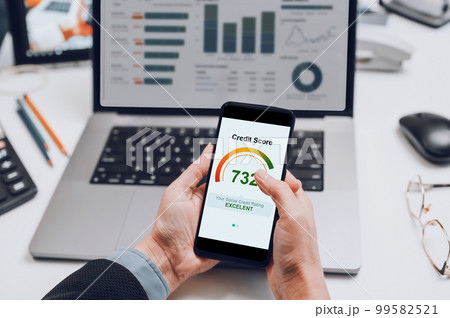 smartphone in hand with a screen with a bank credit report on the background of a laptop. 99582521