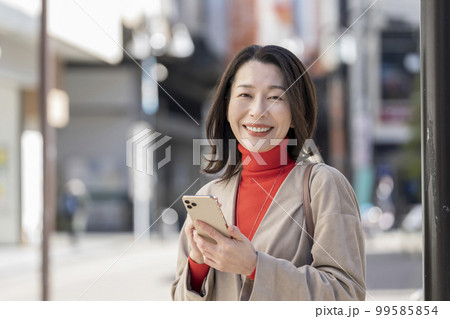 スマートフォンを持ったアラフィフの女性　カメラ目線 99585854