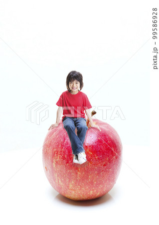 りんご大好き アップルボーイ 巨大りんごに座ってる少年（合成）  99586928