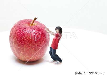 りんご大好き アップルボーイ 巨大りんごを転がそうとしている少年（合成）  99586929