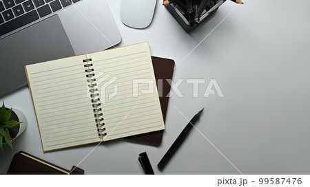 Empty spiral notepad, pen, laptop computer and potted plant on white working desk. Top view, Flat lay 99587476