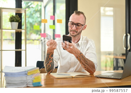 Satisfied man holding credit card and using mobile phone, shopping online, making payment for purchase Satisfied man holding credit card and using mobile phone, shopping online, making payment for purchase 99587557