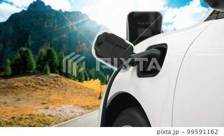 Progressive travel concept by EV car in remote mountain with charging station. 99591162