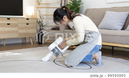 Beautiful woman vacuuming the floor and carpet in her living room, Big cleaning in the house, Removes germs, Housewife cleaning, Keeping her home clean, Domestic hygiene. Beautiful woman vacuuming the floor and carpet in her living room, Big cleaning in the house, Removes germs, Housewife cleaning, Keeping her home clean, Domestic hygiene. 99593005