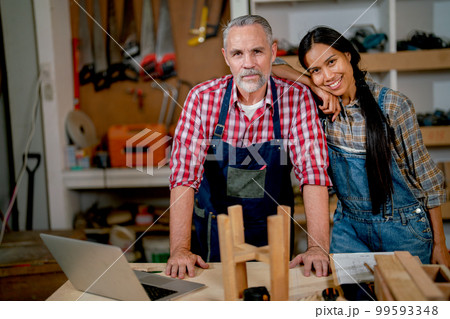 Carpenter lovers stand closely together and look at camera during work in workplace 99593348