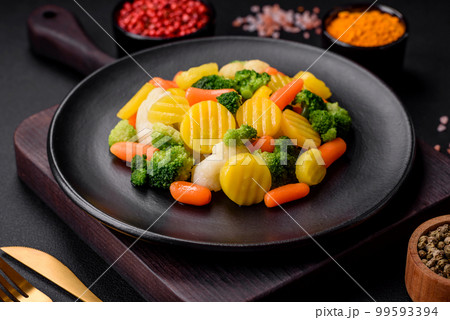Delicious fresh vegetables steamed carrots, broccoli, cauliflower on a black plate Delicious fresh vegetables steamed carrots, broccoli, cauliflower on a black plate 99593394