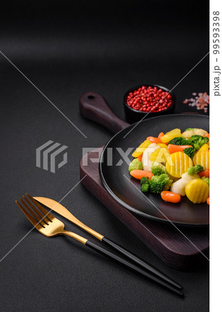 Delicious fresh vegetables steamed carrots, broccoli, cauliflower on a black plate 99593398