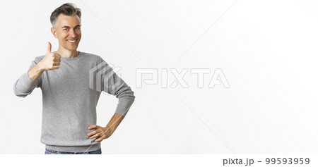 Portrait of proud and happy middle-aged man, smiling pleased and showing thumbs-up, praise something good, standing over white background 99593959