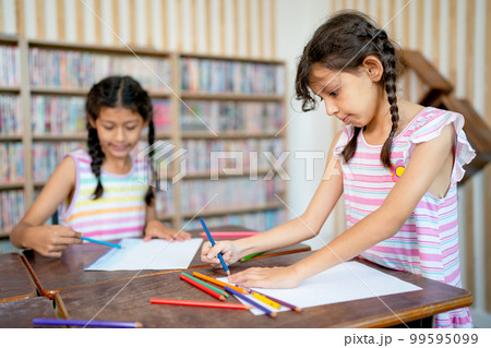 Little Asian girl enjoy to paint the picture with her sister who sit in the back in art classroom Little Asian girl enjoy to paint the picture with her sister who sit in the back in art classroom 99595099