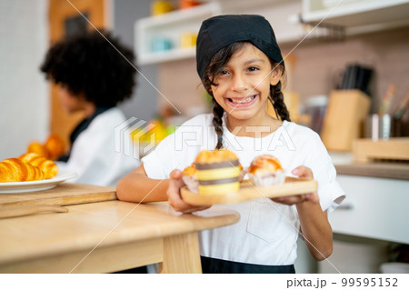 Little lovely girl hold plate contain cupcake and look at camera with smiling during study 99595152