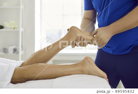Physiotherapist massage male client feet in saloon Physiotherapist massage male client feet in saloon 99595832