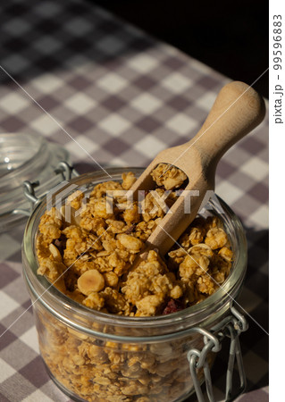 Homemade granola with nuts and seeds in eco glass jar. Healthy snack on breakfast. Muesli from oatmeal, raisins, honey, cranberry, flax, almond, cashew, freshly baked Homemade granola with nuts and seeds in eco glass jar. Healthy snack on breakfast. Muesli from oatmeal, raisins, honey, cranberry, flax, almond, cashew, freshly baked 99596883