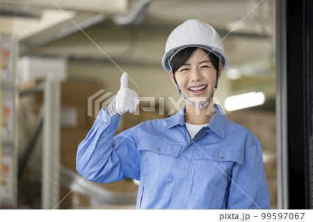 倉庫管理スタッフ　イメージ　笑顔でサムアップする作業服の女性 99597067