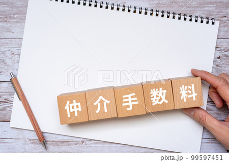 仲介手数料と書かれたブロック、ノート、ペン、手 99597451