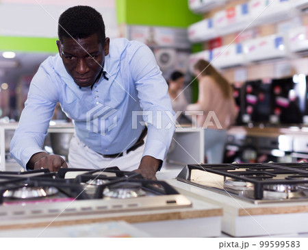 Smiling male selecting new cooking top in store 99599583