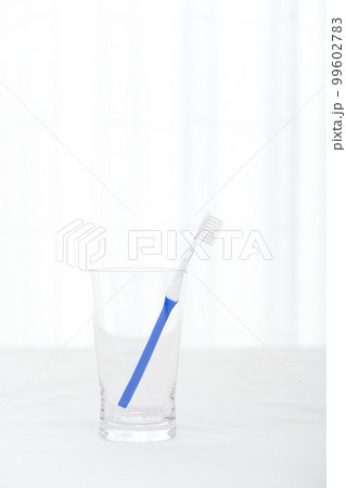 ガラスのコップに青い柄の歯ブラシがさしてある様子 99602783