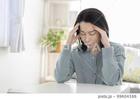 こめかみを押さえるアラフィフの女性　頭痛　イメージ 99604386