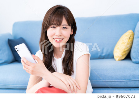 明るいリビングでスマホを使う若い女性 明るいリビングでスマホを使う若い女性 99607073
