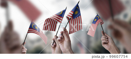 A group of people holding small flags of the Malaysia in their hands A group of people holding small flags of the Malaysia in their hands 99607754